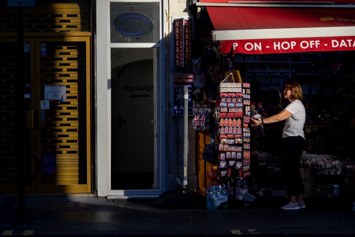 A woman checking a souvenir stand outside a shop in sunlight