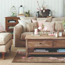 A beige sofa with a matching armchair and pink accessories