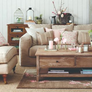 Beige sofa with matching armchairs and pink accessories