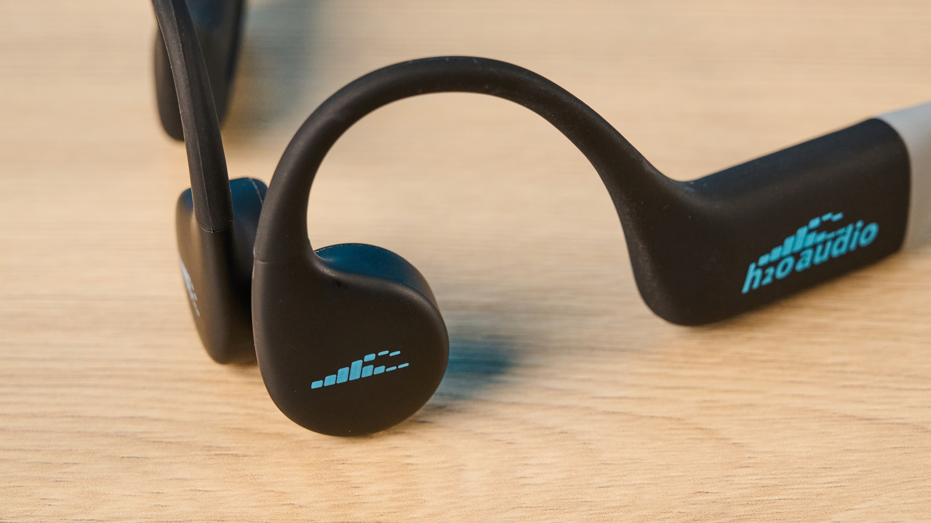the h2o audio tri run bone conduction headphones photographed against a tom's guide blue background