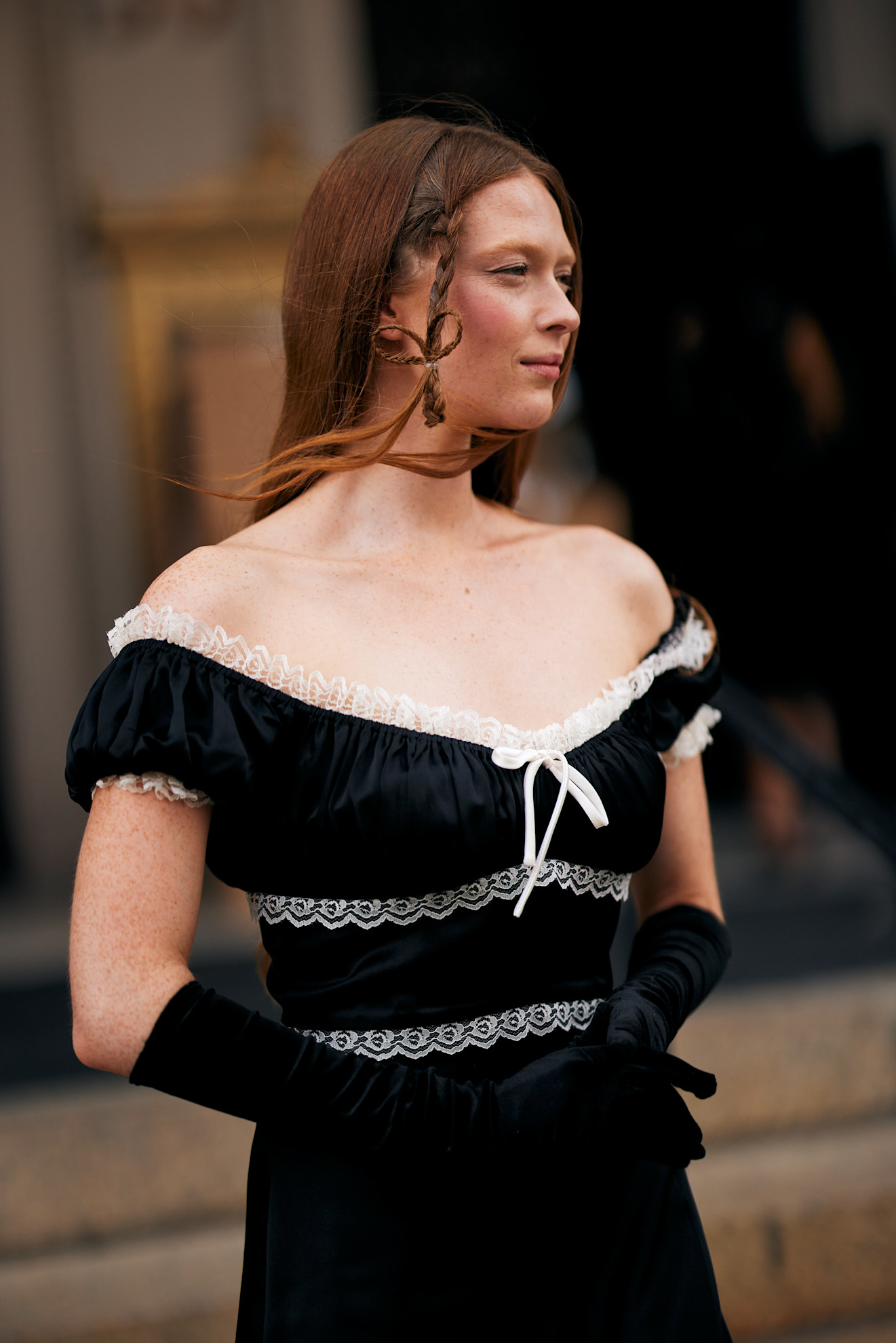 a woman in a black velvet dress with white lace details, red hair with a braid in the front