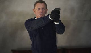 No Time To Die Daniel Craig aims his pistol in a sweater