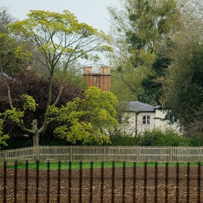 An exterior image of Frogmore Cottage along a fence and large trees
