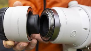 A picture of a photographer holding a white Canon RF 2x Extender