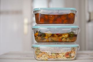 Three containers are stacked on top of each other in the fridge. They contain various cooked foods.