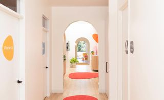 hallway in doctors office with door on both sides, two red round rugs on the floor in front of the reception area