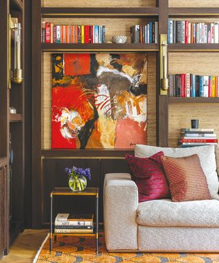 Bespoke dark wood shelving decorated with books, ornaments and artworks, patterned sofa and rug