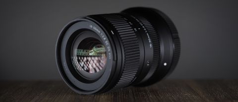 Sigma 18-50mm f/2.8 DC DN | C in Canon RF mount, on a wooden surface against a dark background, moodily lit