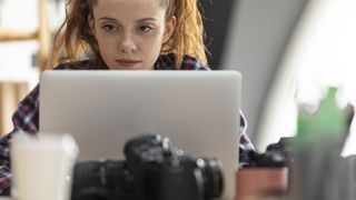 Selective focus shot of young female entrepreneur sitting at her desk at the office and working on laptop.