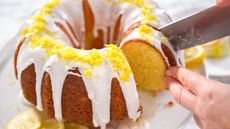 Lemon pound cake being sliced on a cake stand