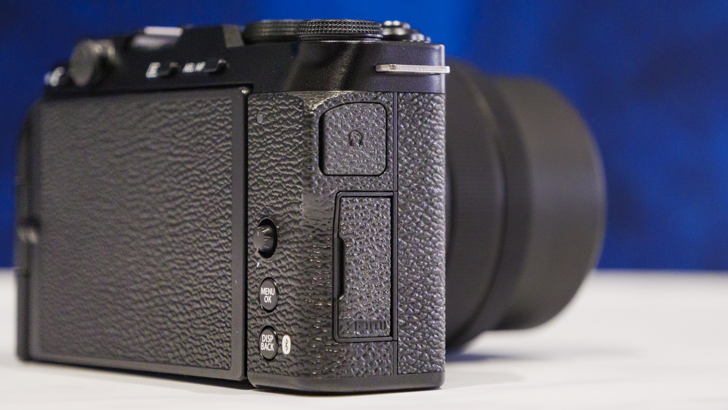 Closeup of the Fujifilm X-M5 camera's ports, on a marble surface with rich blue background