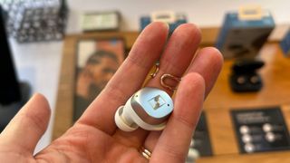 A single Sennheiser Momentum 4 True Wireless earbud being held in a hand