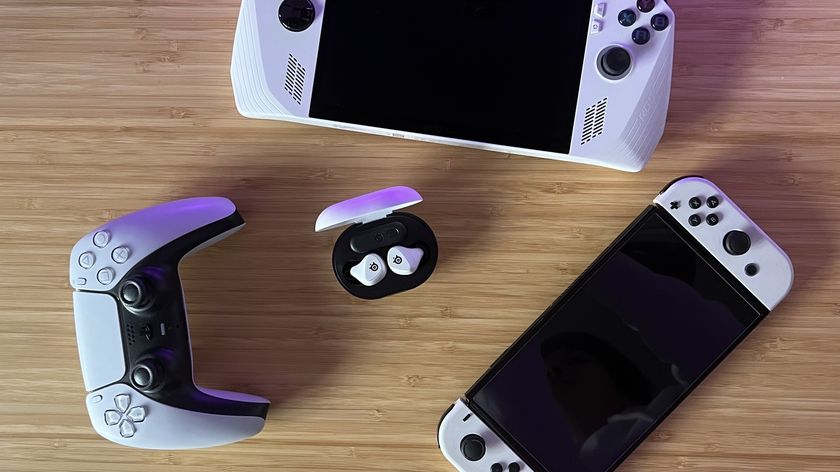 SteelSeries Arctis Game Buds on a wood table with PS5 controller, Nintendo Switch, and Asus ROG Ally