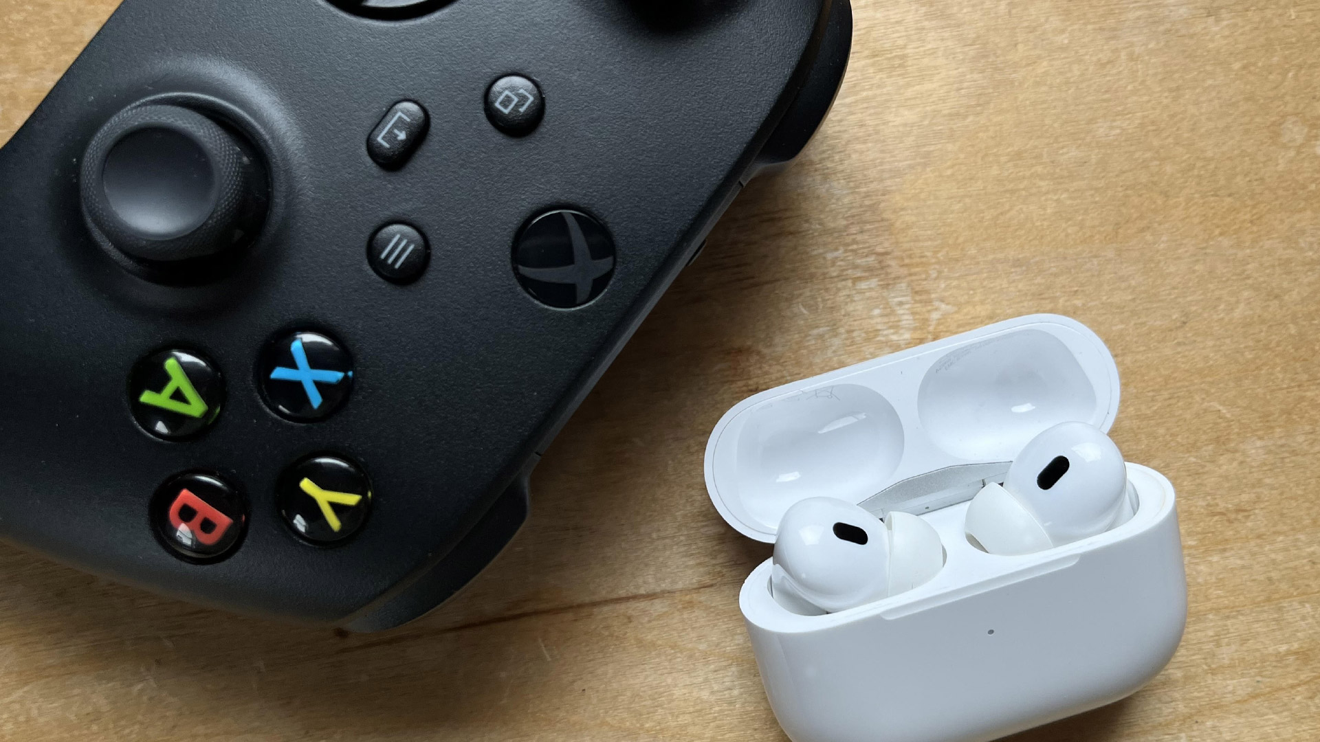 An Xbox controller next to a pair of AirPods