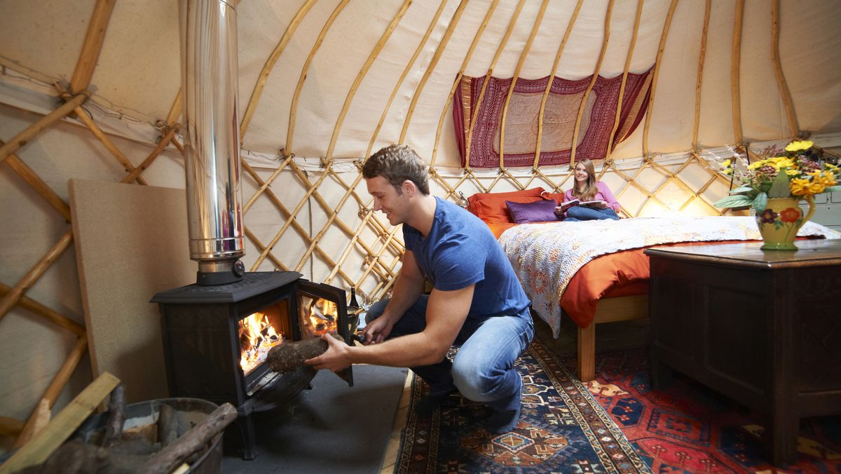 what is winter hot tenting: man putting wood in wood burning stove