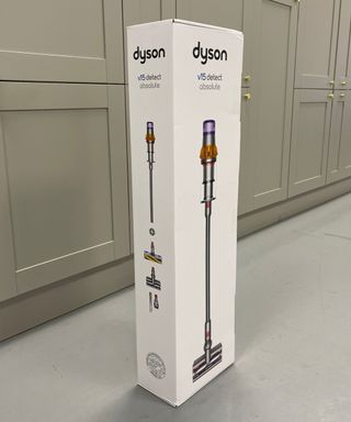 White cardboard Dyson V15 Detect box with the cordless vacuum and its attachments printed on the outside, in front of gray cabinets in Future test center