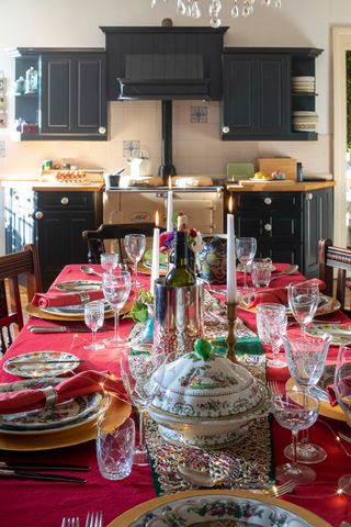 dining table with red cloth and festive details with dark kitchen cabinets and aga behind