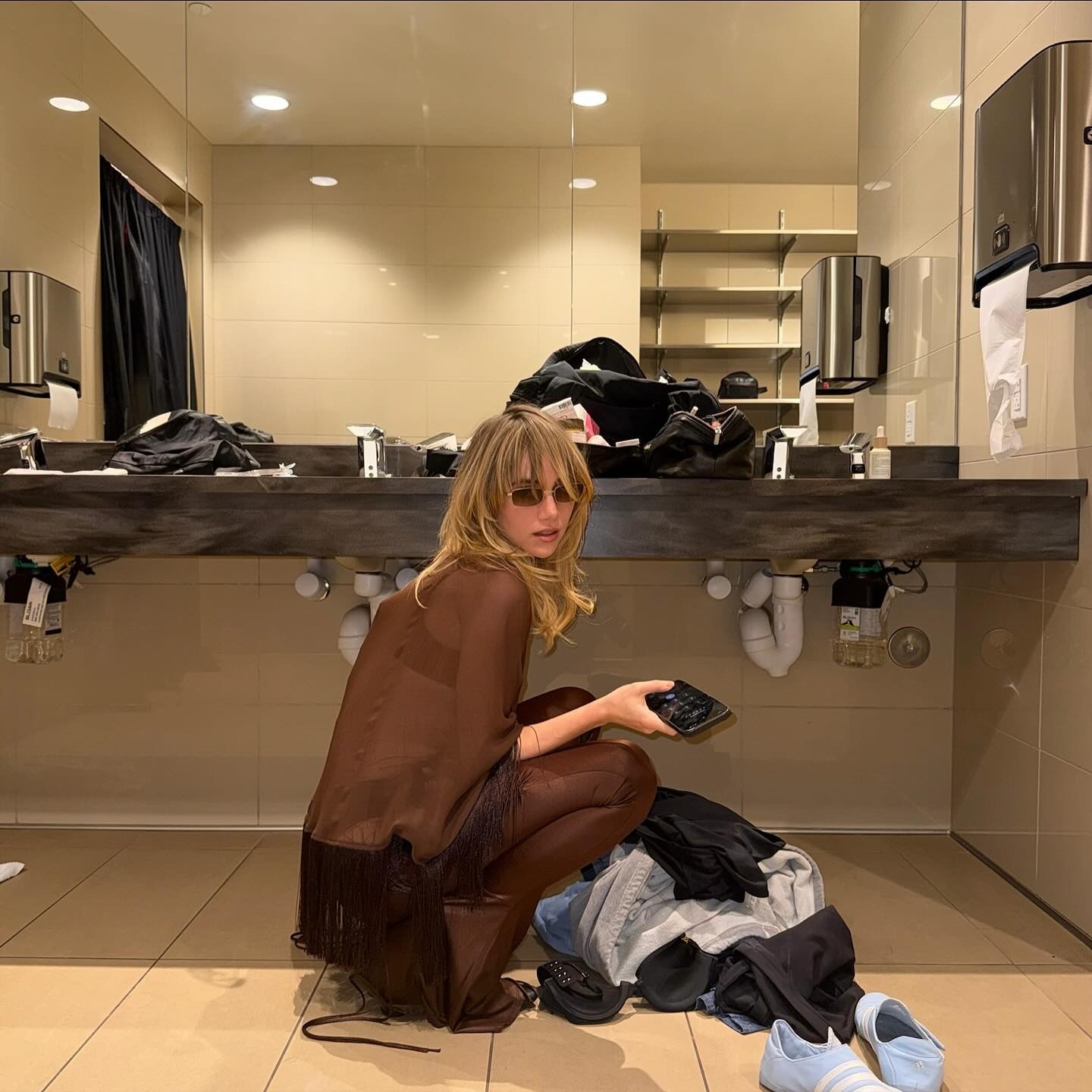 Suki Waterhouse getting ready on tour wearing a chocolate brown outfit with warm blonde hair