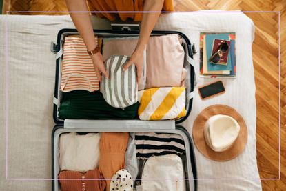 A birds eye view of a woman packing a suitcase with clothes