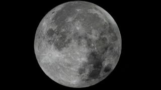 one side of the silvery-grey surface of the moon is slightly darkened by a shadow
