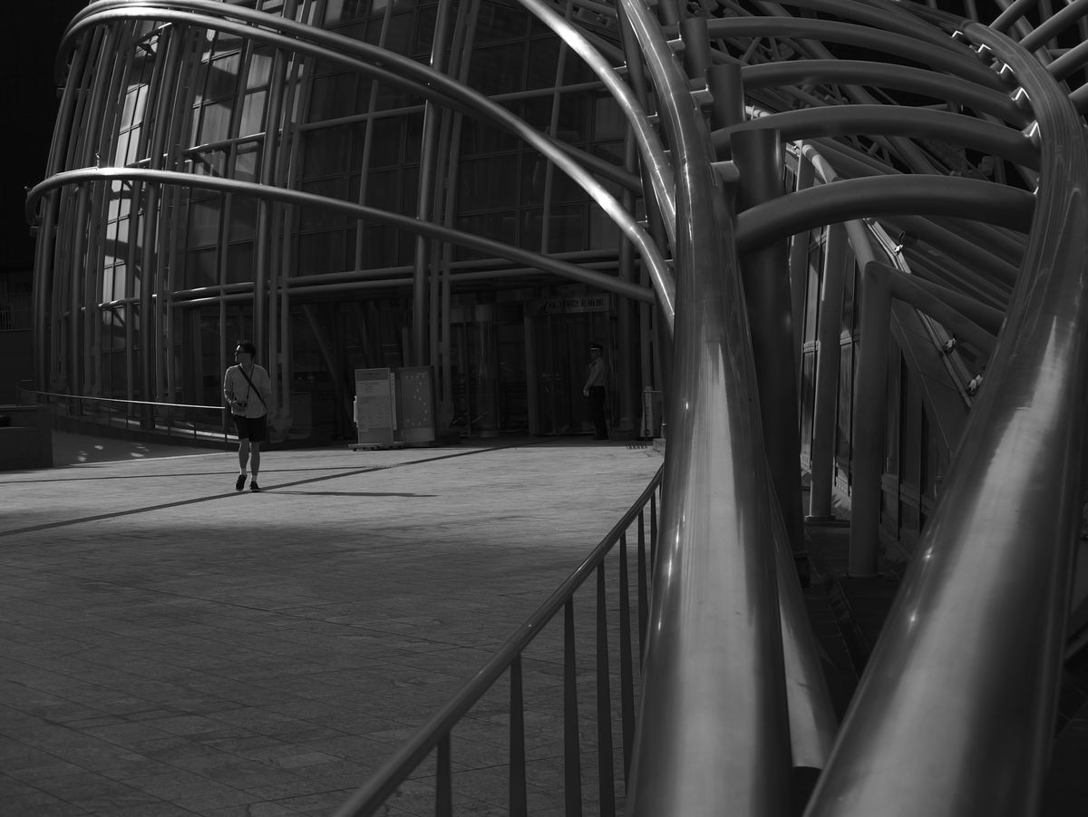 Man walking by the curved steel architecture of a modern building in an urban setting in Japan