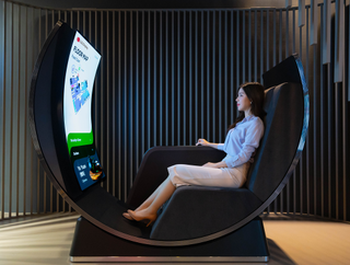 Woman sitting on LG Display Media Chair, a recliner concept by LG featuring flexible OLED television.