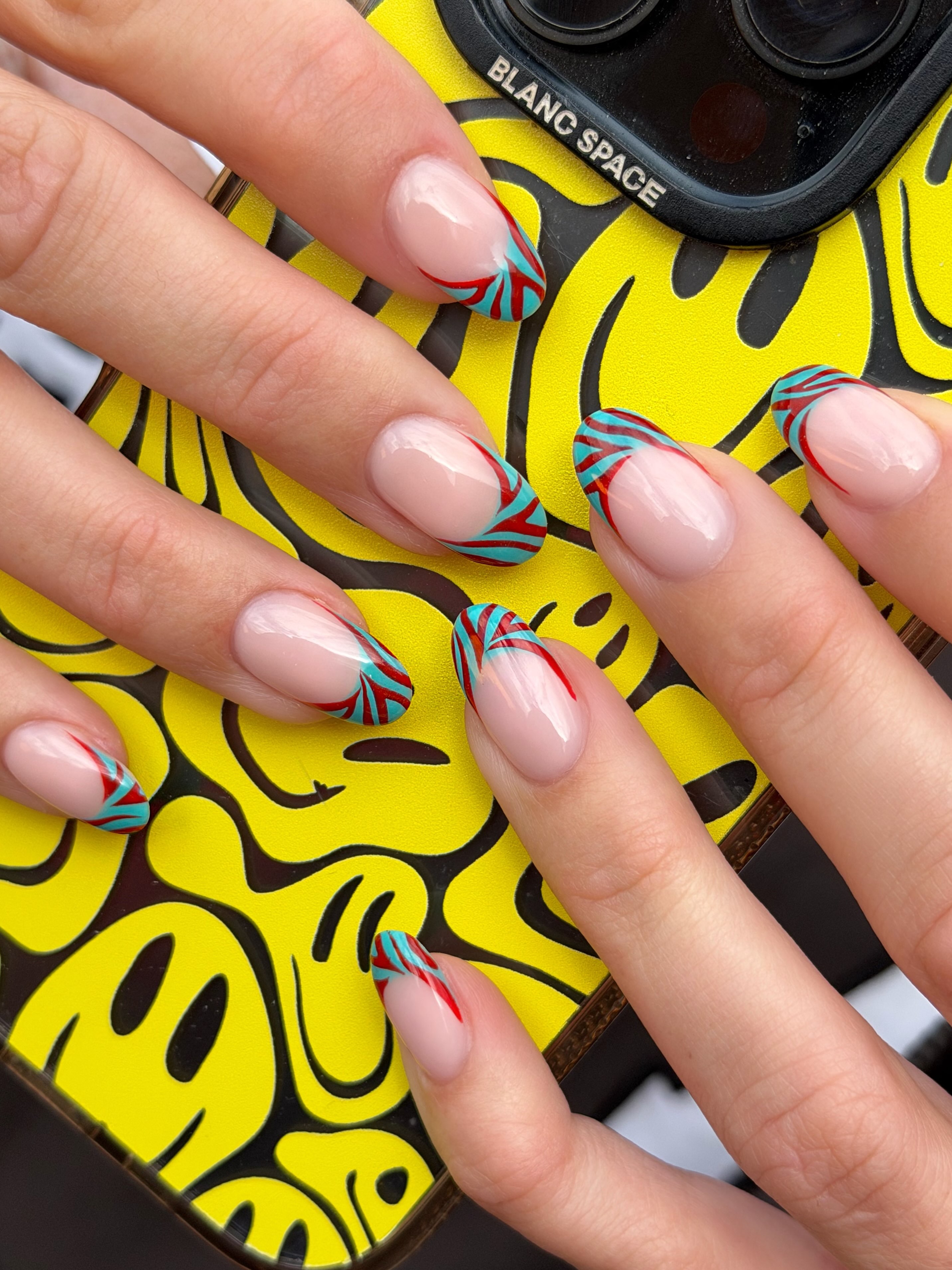 Nude almond nails with colorful burgundy and turquoise zebra print French tips