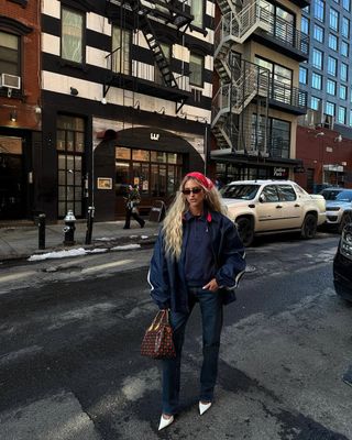 woman wearing navy wind breaker jacket with flare jeans with stiletto heels