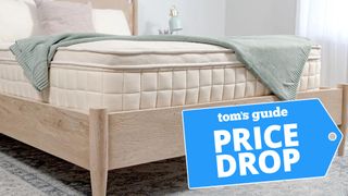 A Close up of the foot of the Naturepedic Concerto Plush Pillow Top Mattress on a bed frame in a bedroom, a Tom's Guide price drop deals graphic (right)