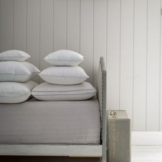Pile of pillows on top grey and white striped mattress