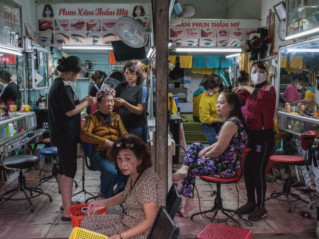 A busy beauty salon with multiple clients receiving services, surrounded by mirrors and hair care products, colorful decor enhances the atmosphere