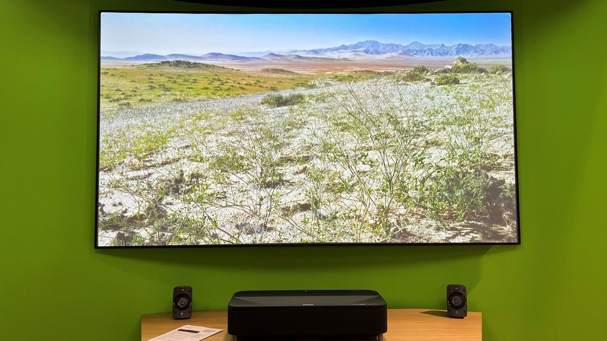 Epson EH-LS800B UST projector on a table with screen in background