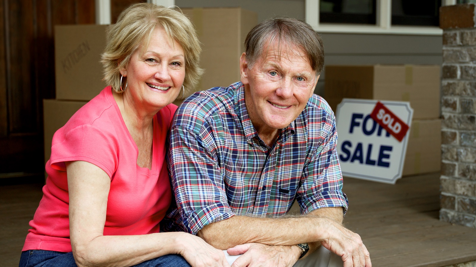 A senior couple sitting on the porch of the house that just sold.