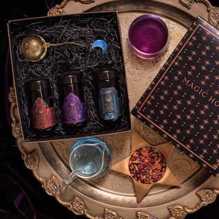 A Magic Hour tea gift set with three glass bottles of tea and a strainer with an opalite moon charm