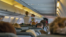 Two flight attendants make their way through an aircraft cabin