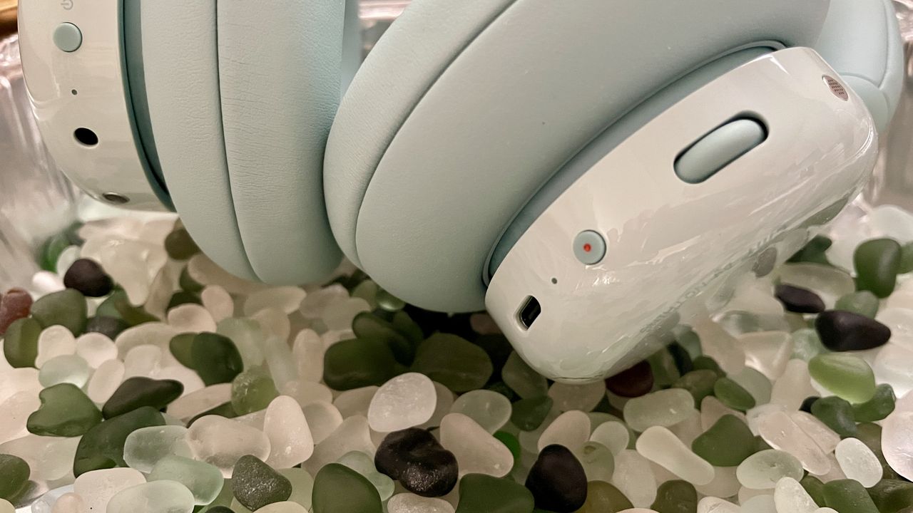 CMF Headphone Pro in pistachio green held in a hand or hung on a barbell, being pushed up by a carved frog