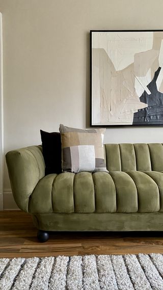 A living room with a green velvet sofa decorated with cushions