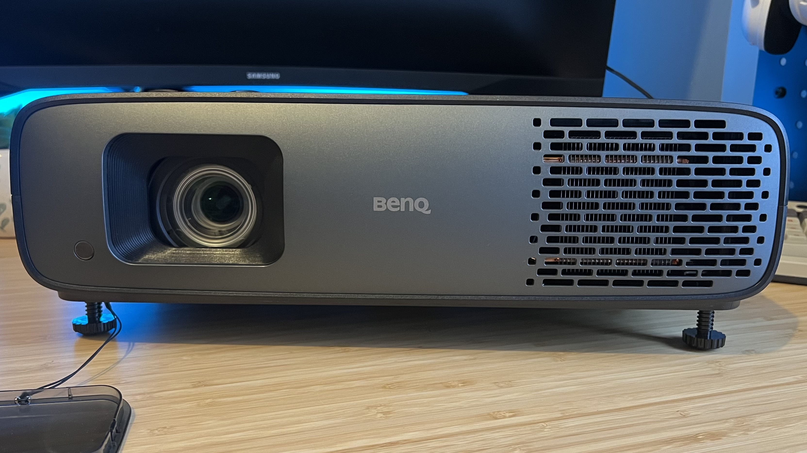 BenQ W4100i projector with lens cap removed on a wooden desk
