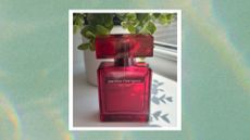 Image of red bottle of Narciso Rodriguez For Her Eau de Parfum Intense standing in the sun, in front of green leafy plant and window, on a green marbled background