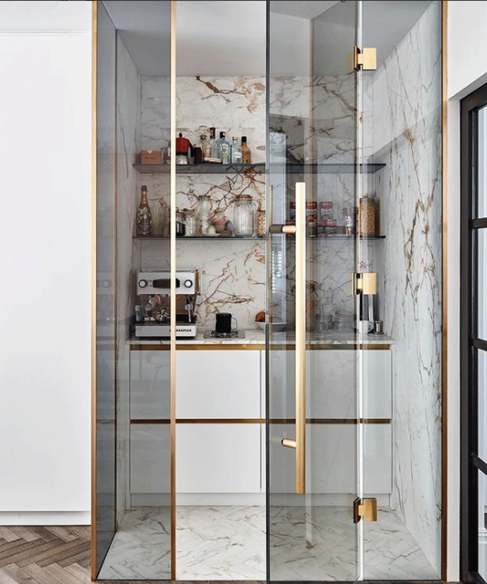 Pantry with marble-clad walls and a glass door with gold fittings