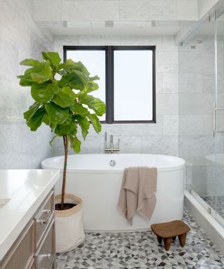 modern marble bathroom with freestanding bathtub and a large plant