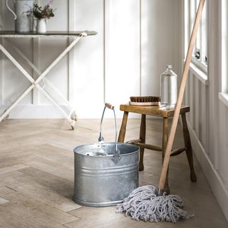 room with white wall and wooden flooring with mop stick