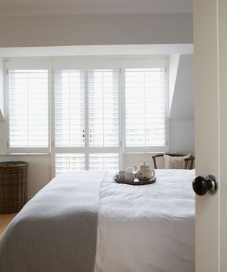 West Sussex new build. Neutral grey bedroom, colonial window shutters