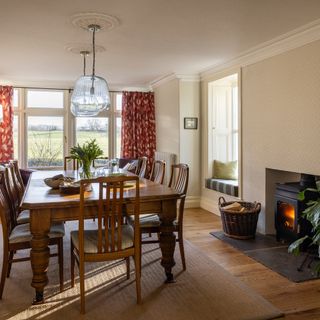 country dining room wuth antique wooden table and chairs, log burner and window seats to country views