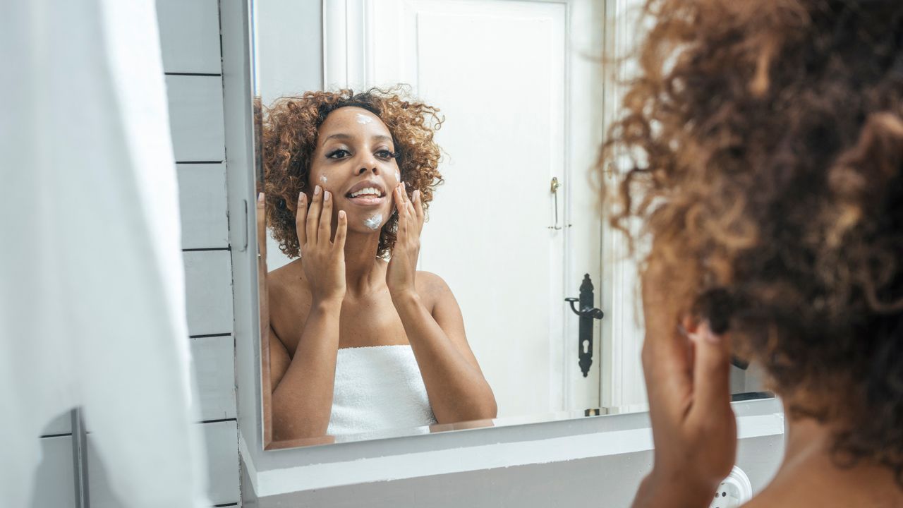 Woman using coconut oil in the mirror as a moisturiser