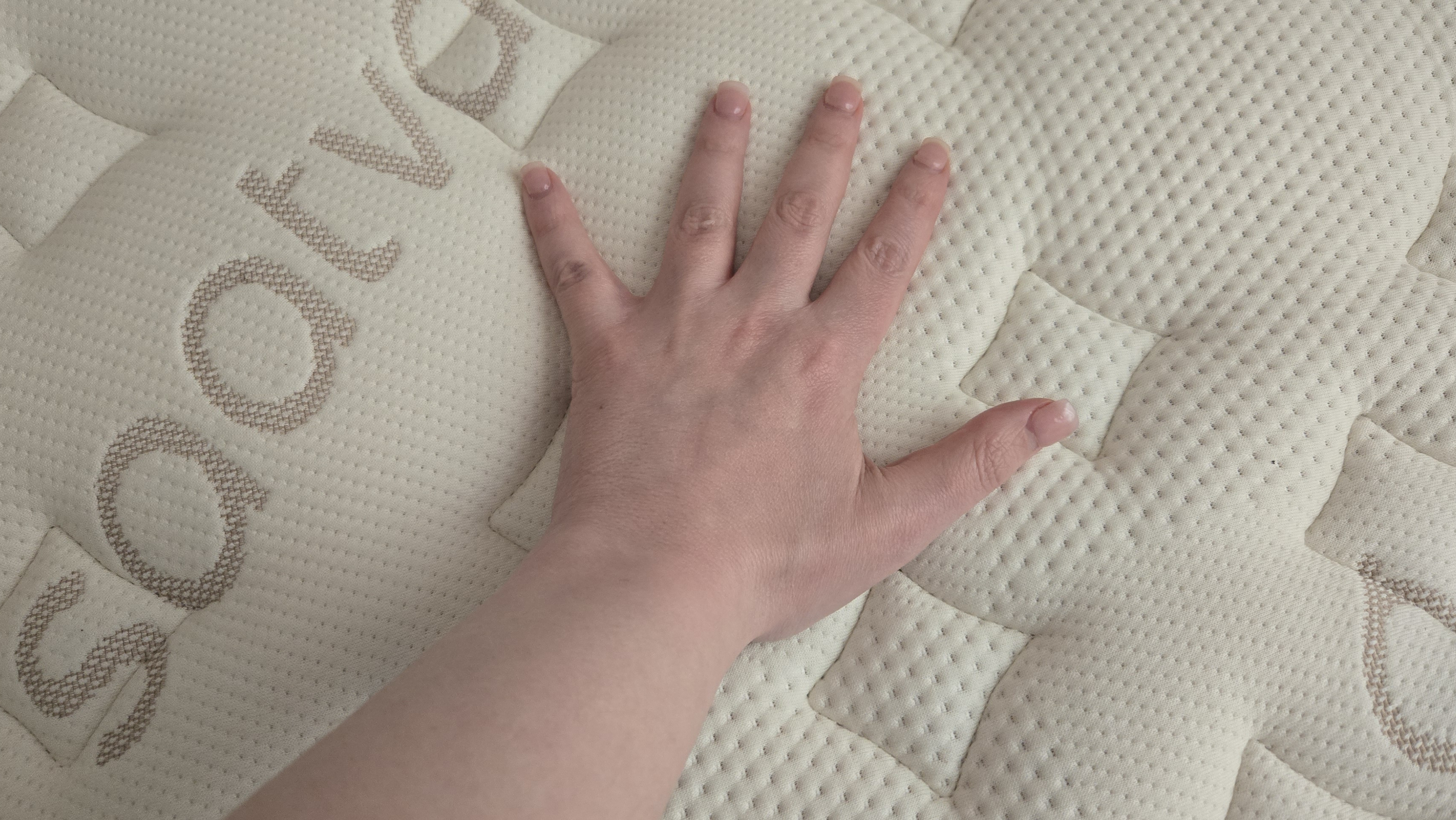 Saatva Memory Foam Hybrid Mattress with hand on the top cover