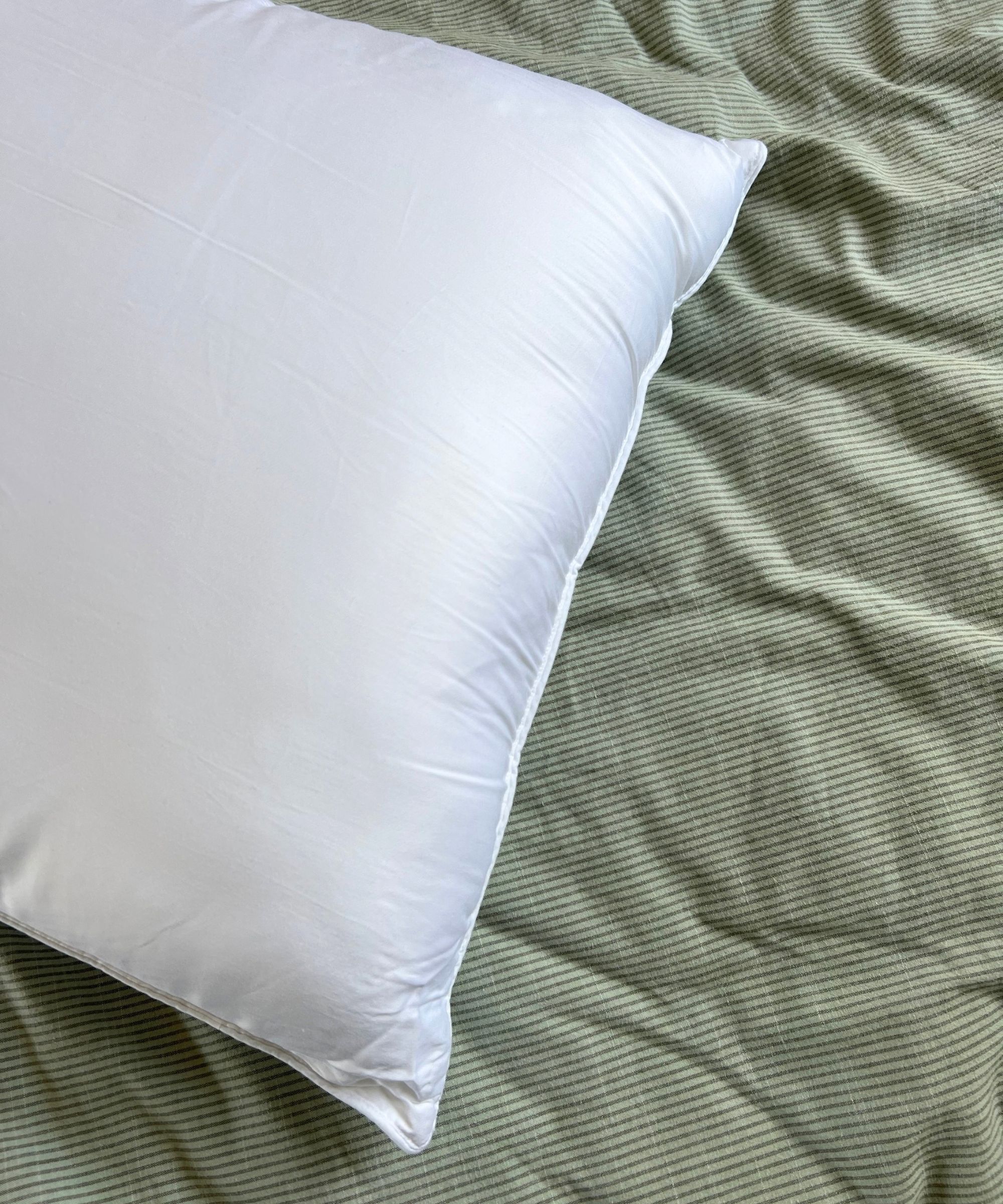 Cozy Earth Bamboo Down Alternative Pillow pictured on a green striped bedding set.