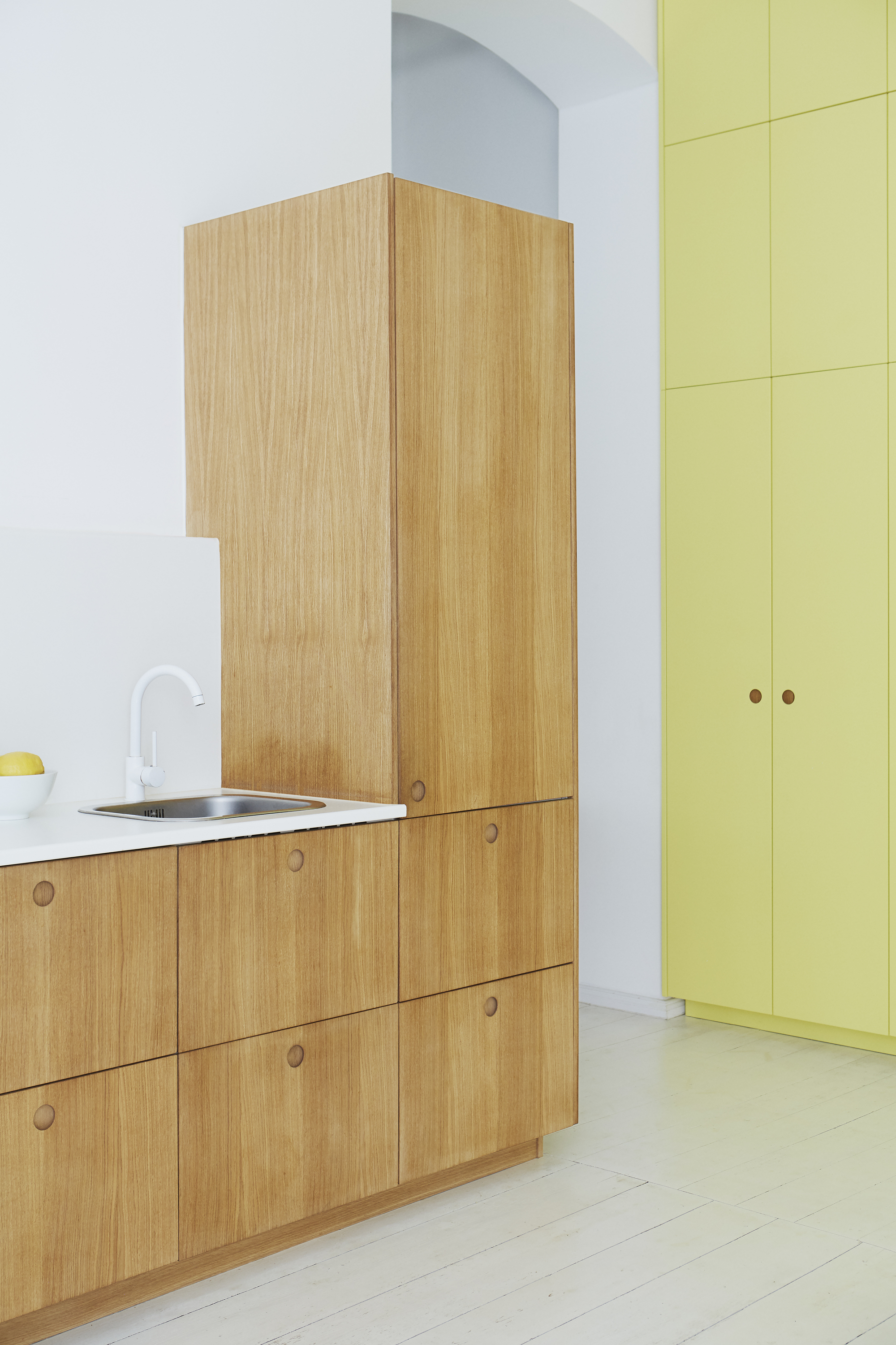 tangy yellow kitchen cabinets, timber galley kitchen with white countertops, white tap, white walls, and painted white floorboards