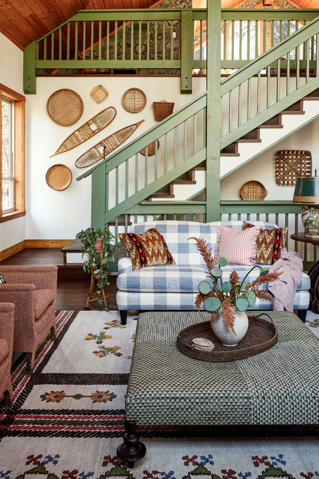 Rustic great room featuring an eclectic mix of wall art, collected objects, and upholstered furniture &ndash; the gingham loveseat being the most statement-making of the bunch