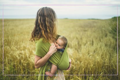 Babywearing mother breastfeeding in a field